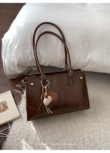 Détails du sac fourre-tout marron vintage avec boucle argentée et pendentif cœur sur tapis