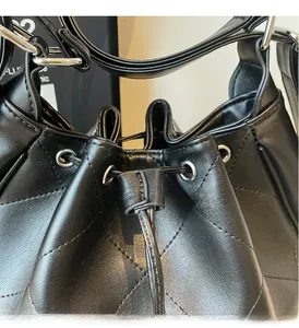 Détail du sac fourre-tout en cuir noir matelassé avec cordon de serrage et œillets en argent