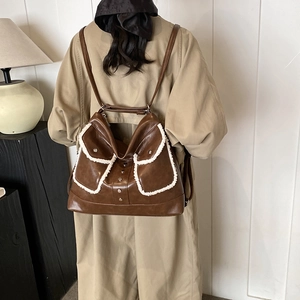 Brown vintage faux leather backpack with white faux fur trim and metal studs worn by model
