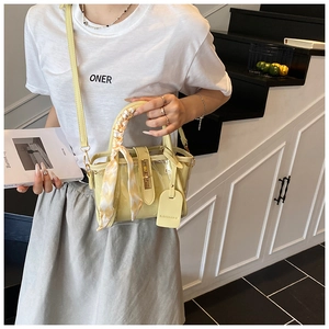 Detail of yellow translucent bucket bag featuring a silk scarf handle and metal clasp