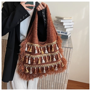 Détail du sac hobo en tricot marron caramel avec dentelle dorée et franges bohèmes