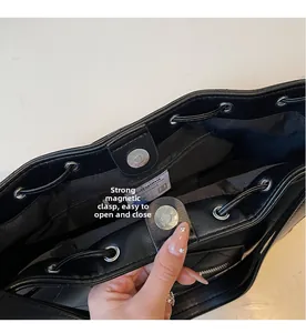 Détail du sac cabas en cuir noir avec boucle magnétique argentée et cordon de serrage