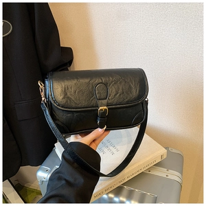 Close-up of black PU leather shoulder bag featuring vintage pleats and gold buckle