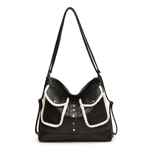 Black leather shoulder bag with white fleece trim and dual front pockets with silver studs