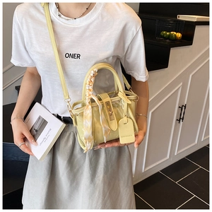 Close-up of yellow PVC bucket bag with leather handles and decorative silk scarf detail