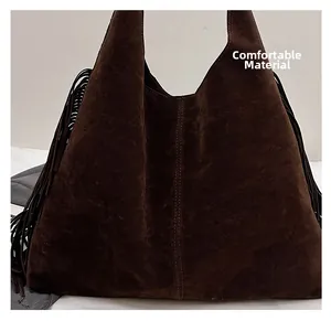 Dettaglio ravvicinato della borsa a spalla in pelle scamosciata marrone con frange e cuciture