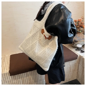 Detailed close-up of ivory knit tote bag featuring leather patch and wood horn button