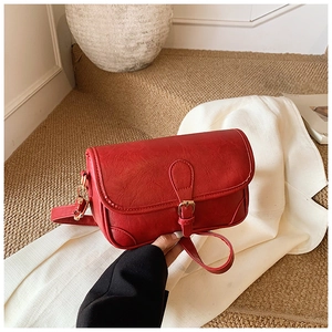Detail shot of a red vintage crossbody bag with litchi leather texture and gold metal buckle