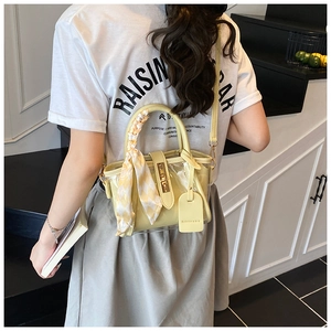 Detail of yellow mini bucket bag with scarf-wrapped handle and transparent PVC stitching