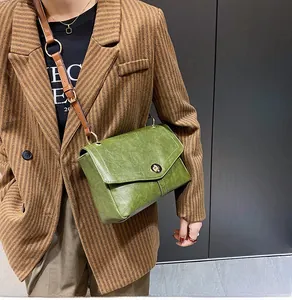 Détail du sac vintage en cuir vert avec fermoir en métal et bandoulière marron