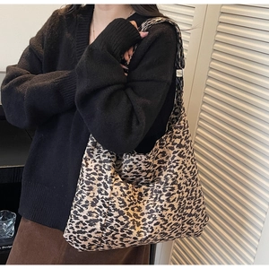 Close-up of leopard print hobo tote bag featuring a wide shoulder strap on a model