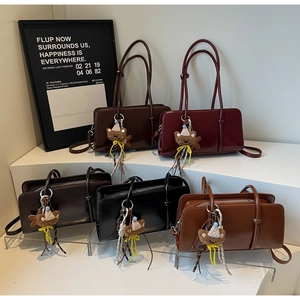 Détail de sacs à bandoulière rectangulaires en cuir brillant avec pendentifs ours peluche
