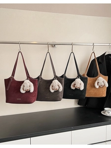 Detail view of four textured suede tote bags in various colors with cute rabbit ear charms