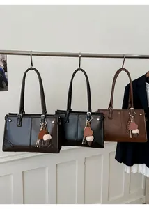 Trois cabas en cuir noir et marron avec breloques cœur suspendus à une barre