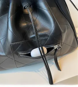Détail macro du sac à dos en cuir matelassé noir montrant la poche zippée et les écouteurs