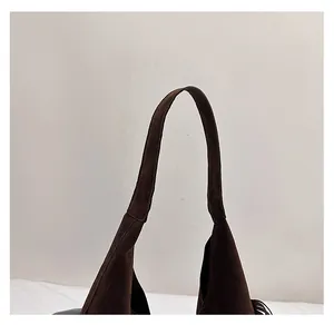 Dettaglio del manico in camoscio marrone scuro e cuciture resistenti sulla borsa tote