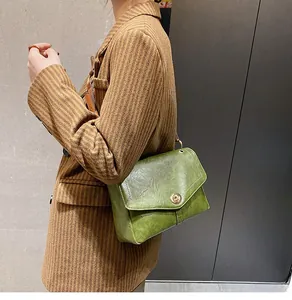 Détail d'un sac messager vintage vert en similicuir avec un fermoir rond en métal