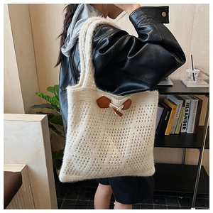 Detail of off-white knit tote bag with hollow crochet texture and brown toggle closure
