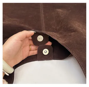 Dettaglio della doppia chiusura magnetica su una borsa tote in pelle scamosciata marrone