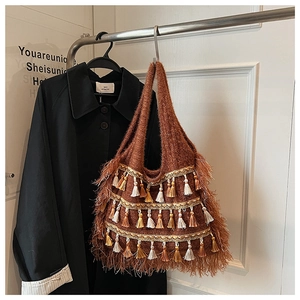 Détail de sac cabas bohème en maille marron avec des franges bicolores et pompons soignés