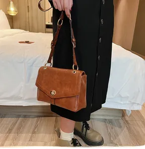 Gros plan détaillé du sac en cuir marron grainé avec anneau doré et fermoir rotatif