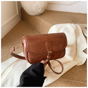 Detail of vintage brown leather bag with metallic buckle and natural pleated texture