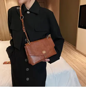 Sac bandoulière rétro en cuir marron avec fermoir rotatif porté par un mannequin