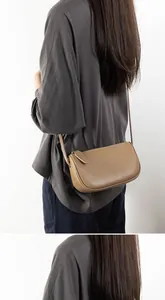 Detail of minimalist earthy brown leather crossbody bag with zipper and slim shoulder strap