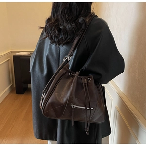 Vue de dos d'un modèle portant un grand sac seau matelassé marron foncé avec cordon de serrage