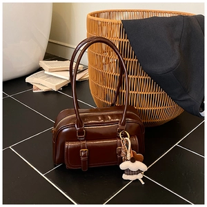 Detail view of deep brown vintage Boston bag with oil-wax texture and plush puppy charm