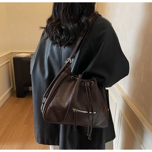 Detail of dark brown quilted drawstring tote with silver zipper and adjustable strap