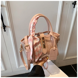 Detailed close-up of pink transparent bucket bag with plaid scarf wrapped handle and lock