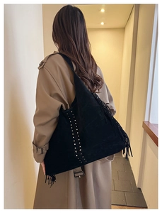 Dettaglio di borsa tote in pelle scamosciata nera con frange e borchie a stella