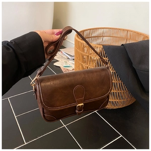 Detail of vintage dark brown shoulder bag with retro buckle and textured leather finish