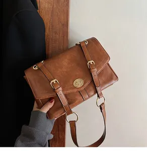 Détail d'un sac bandoulière rétro marron avec fermoir rotatif en métal doré chic