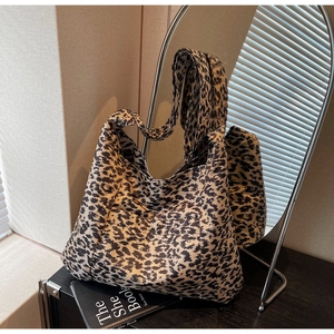 Detail of large leopard print tote bag with wide strap on a wooden table setup
