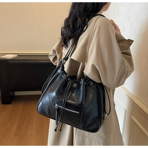 Détail d'un sac cabas noir matelassé avec motif à losanges porté par un mannequin