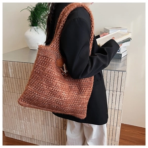 Caramel cable knit tote bag with retro leather horn button detail on a model's shoulder