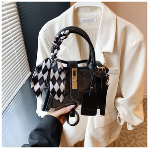 Detail of black transparent PVC bucket bag with gold lock and checkered scarf handle