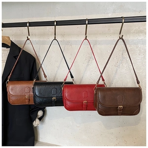 Row of retro PU leather messenger bags in four colors hanging on a textured wall