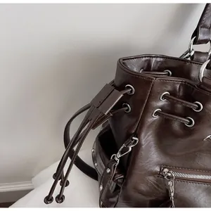 Detailed close-up of dark brown PU leather bucket bag with silver eyelets and drawstring