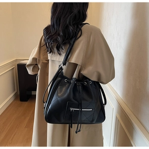 Detail of black quilted bucket bag with drawstring closure and silver zipper pocket