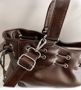 Detail of silver metal hook and leather strap on a vintage dark brown tote bag