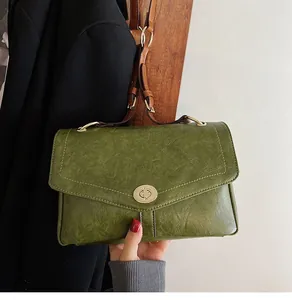 Détail du sac messager vintage vert foncé en cuir texturé avec fermoir doré