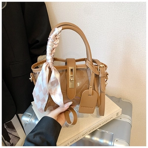Detail of PVC bucket bag with leather trim and decorative silk scarf on handle