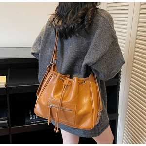 Brown quilted drawstring tote bag with diamond texture worn by model in casual scene