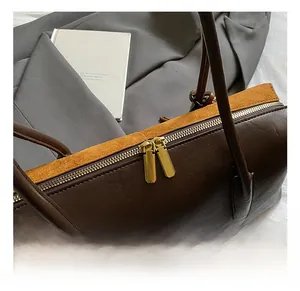Detail of dark brown leather and yellow suede bag with golden dual metal zippers