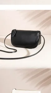 Detail of minimalist black cylindrical crossbody bag with zipper and soft leaf shadows