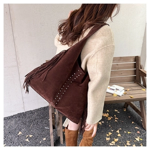 Dettaglio borsa tote in pelle scamosciata marrone con frange boho e rivetti a stella