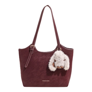 Minimalist burgundy suede tote bag with long shoulder straps and plush rabbit charm